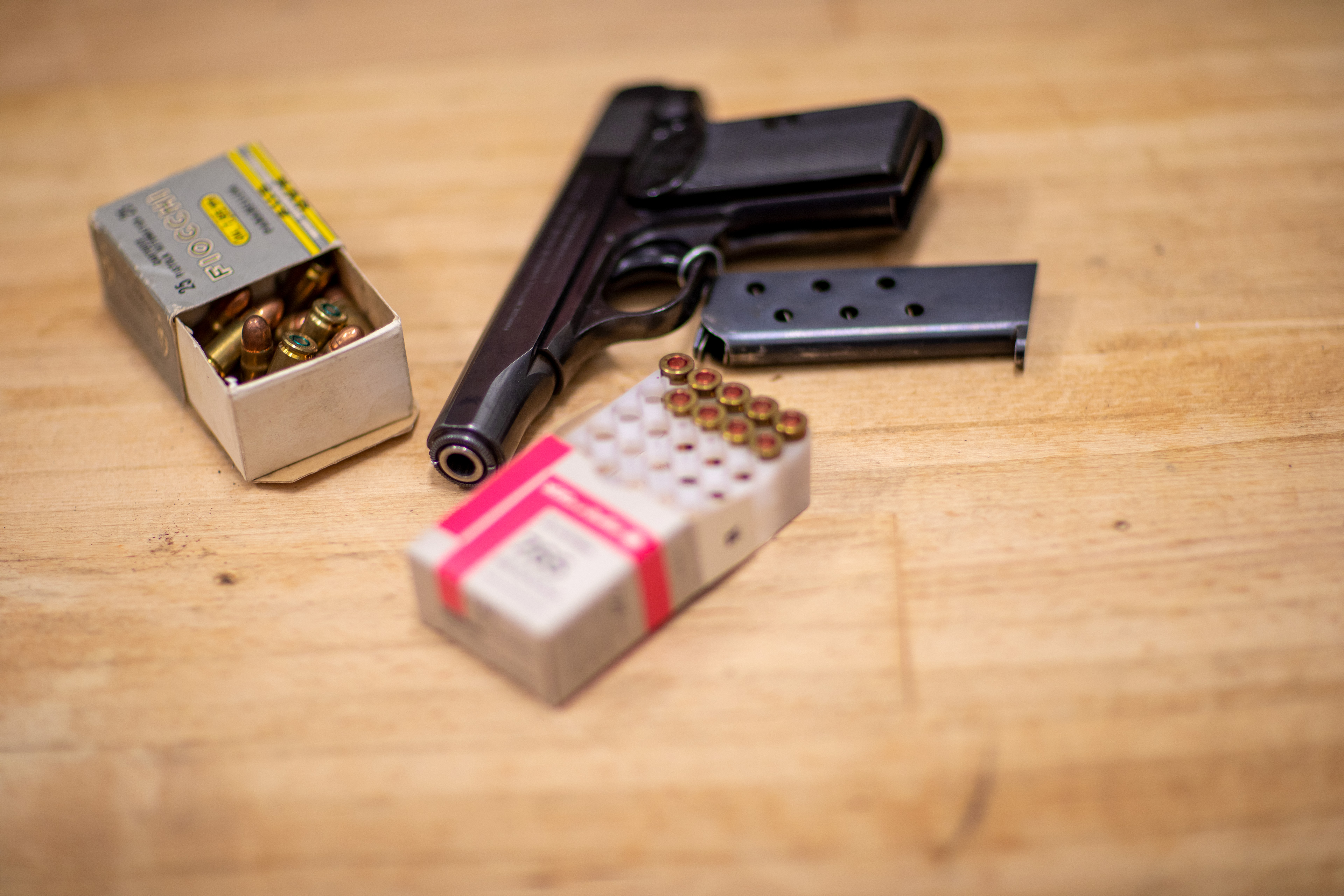 A firearm lies on a table along with ammunition