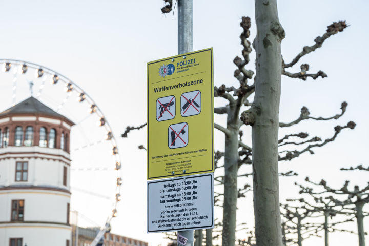 Yellow sign ‘No weapons zone’ attached to a metal pole